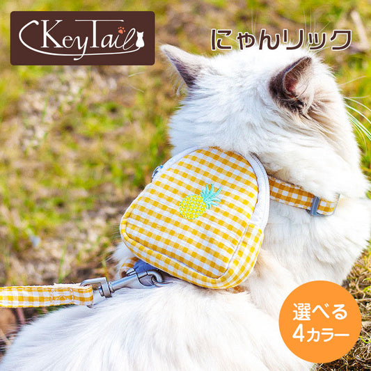 KeyTailのにゃんリュック。イエローのギンガムチェック柄でパイナップル刺繍のミニリュック付きハーネス&リードを装着した白猫のアップ。選べる4カラーの表記あり