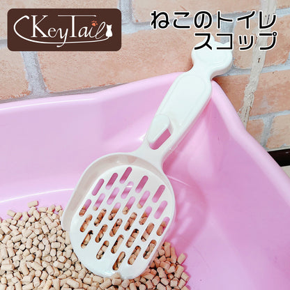 「ねこのトイレスコップ」のロゴ入り紹介カット。アイボリーの猫耳型スコップがピンクのトイレ容器に立てかけられ、目の細かい網目で小粒の猫砂をすくっている