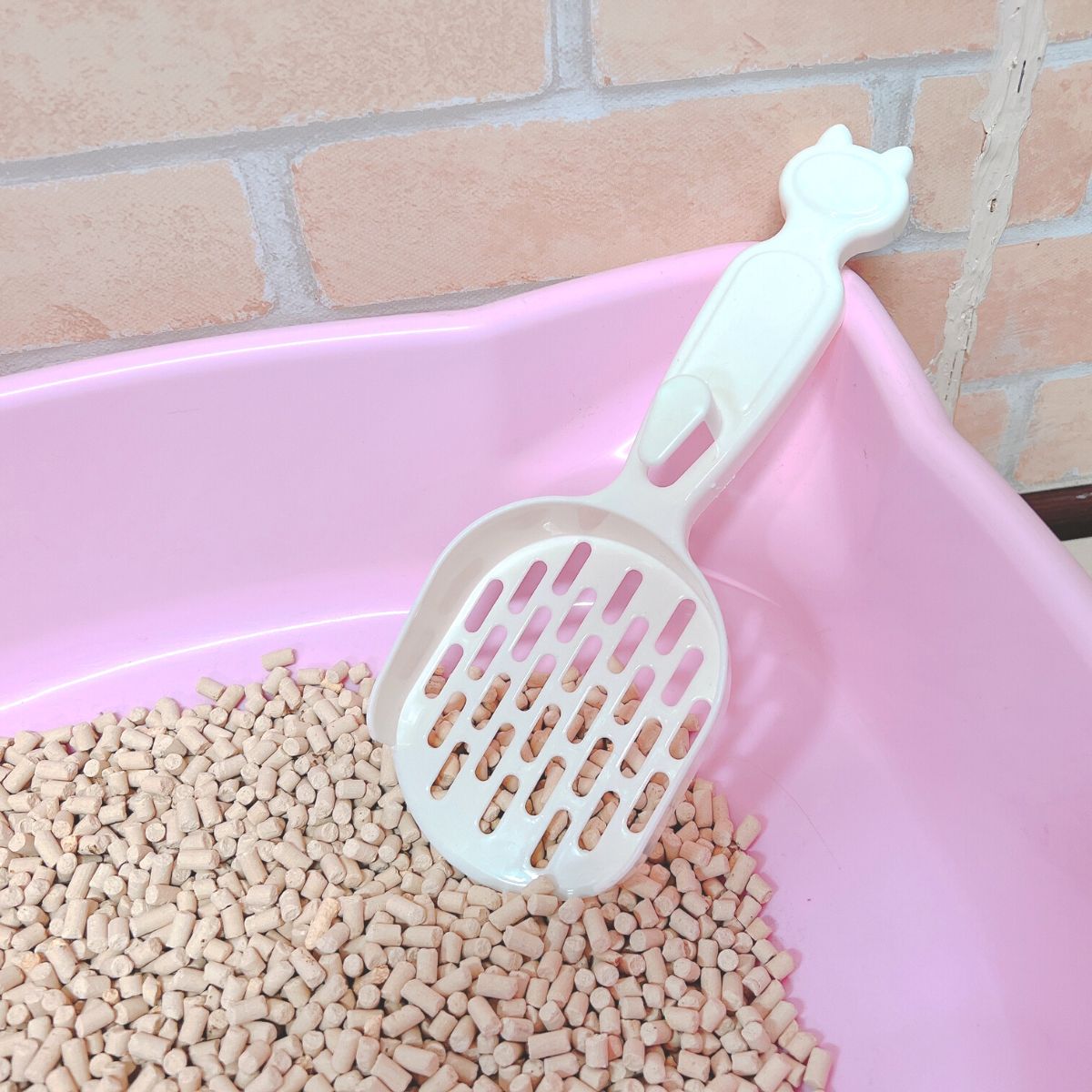 猫耳型の持ち手をトイレ容器のふちに引っかけて立てかけた状態を上から見た図。すくい部分は小粒の猫砂の中に差し込まれている