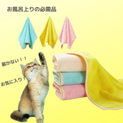 お風呂上がりの必需品という見出し。ブルー・イエロー・ピンクの小さめタオル3枚と、重ねて畳んだ厚手タオル、後ろ足で立ち上がってタオルに手を伸ばす猫