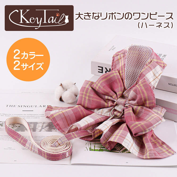 商品名「大きなリボンのワンピース(ハーネス)」のメイン画像。オレンジ丸に「2カラー2サイズ」の表記、チェック柄のリボン付きワンピースハーネスとお揃いリードを本の上にディスプレイ