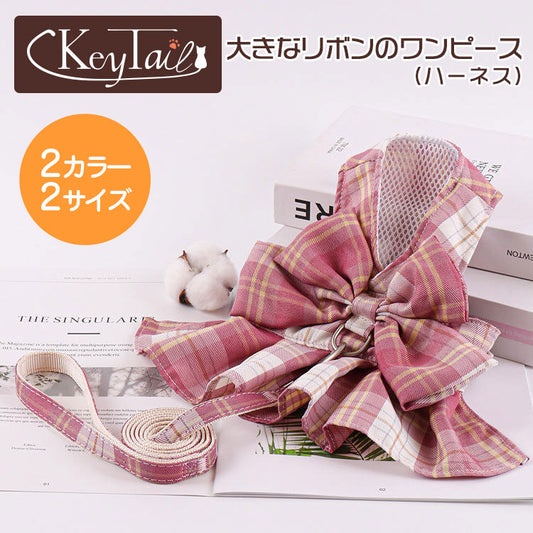 商品名「大きなリボンのワンピース(ハーネス)」のメイン画像。オレンジ丸に「2カラー2サイズ」の表記、チェック柄のリボン付きワンピースハーネスとお揃いリードを本の上にディスプレイ