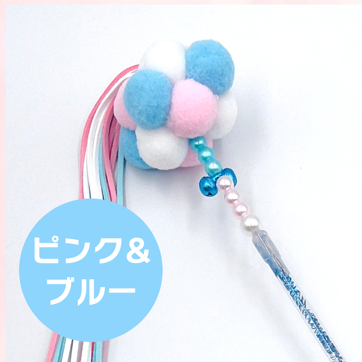 ピンク＆ブルーカラーのもこもこボール部分のクローズアップ写真。青・白・ピンクのポンポンと鈴付きビーズが写る