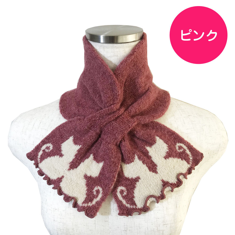 ピンクのマフラーをトルソーの首元で交差結びした着用例。裾にアイボリー色の猫のシルエット模様が編み込まれている