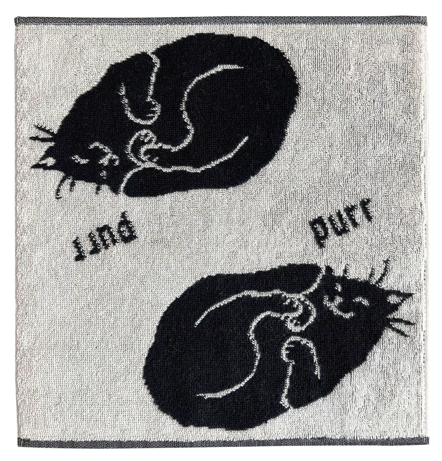 白地に黒猫が丸まって眠る柄のタオル。「purr」の文字入り