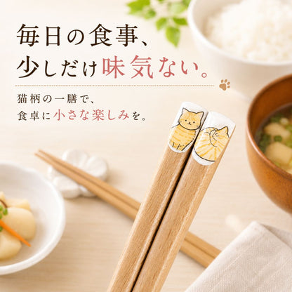 「毎日の食事、少しだけ味気ない。猫柄の一膳で、食卓に小さな楽しみを。」の文字。ご飯と味噌汁の並ぶ食卓で茶トラ猫柄の箸先を立てたカット