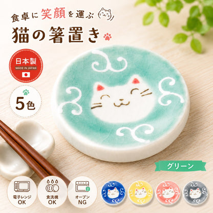 グリーンの猫箸置きのアップ。唐草模様の中に微笑む白猫の顔、手前に木製箸と箸置きが置かれ、右下に他4色を小さく表示