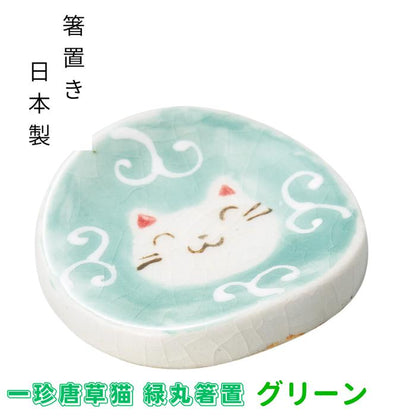 グリーンの一珍唐草猫 緑丸箸置。淡い緑地に唐草模様と微笑む白猫の顔を描いた丸い陶器箸置き、箸置き・日本製の表記