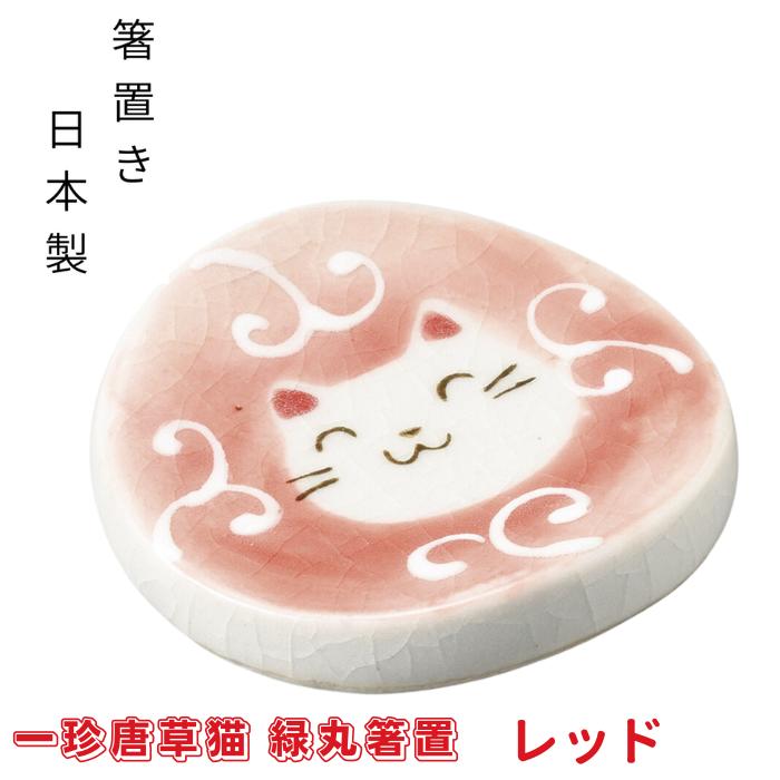 レッドの一珍唐草猫 緑丸箸置。ピンクがかった赤地に唐草模様と微笑む白猫の顔を描いた丸い陶器箸置き、箸置き・日本製の表記