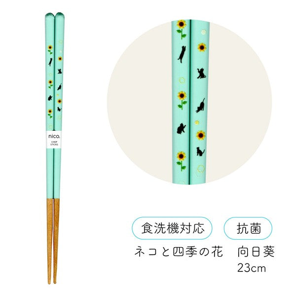 ミント色の向日葵柄。猫シルエットとひまわりの花柄が入った箸の全体と拡大図、「食洗機対応」「抗菌」表記、カラー名は向日葵・23cm