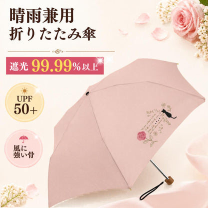 開いたピンク色の晴雨兼用折りたたみ傘。「遮光99.99%以上」「UPF50+」「風に強い骨」の訴求とバラ・黒猫の刺繍柄が入る