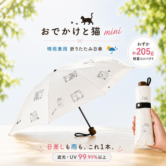 「おでかけと猫mini」ロゴと猫のイラスト付きオフホワイトの日傘。晴雨兼用の折りたたみ日傘で重さ約205g、遮光・UVカット99.99%以上を訴求