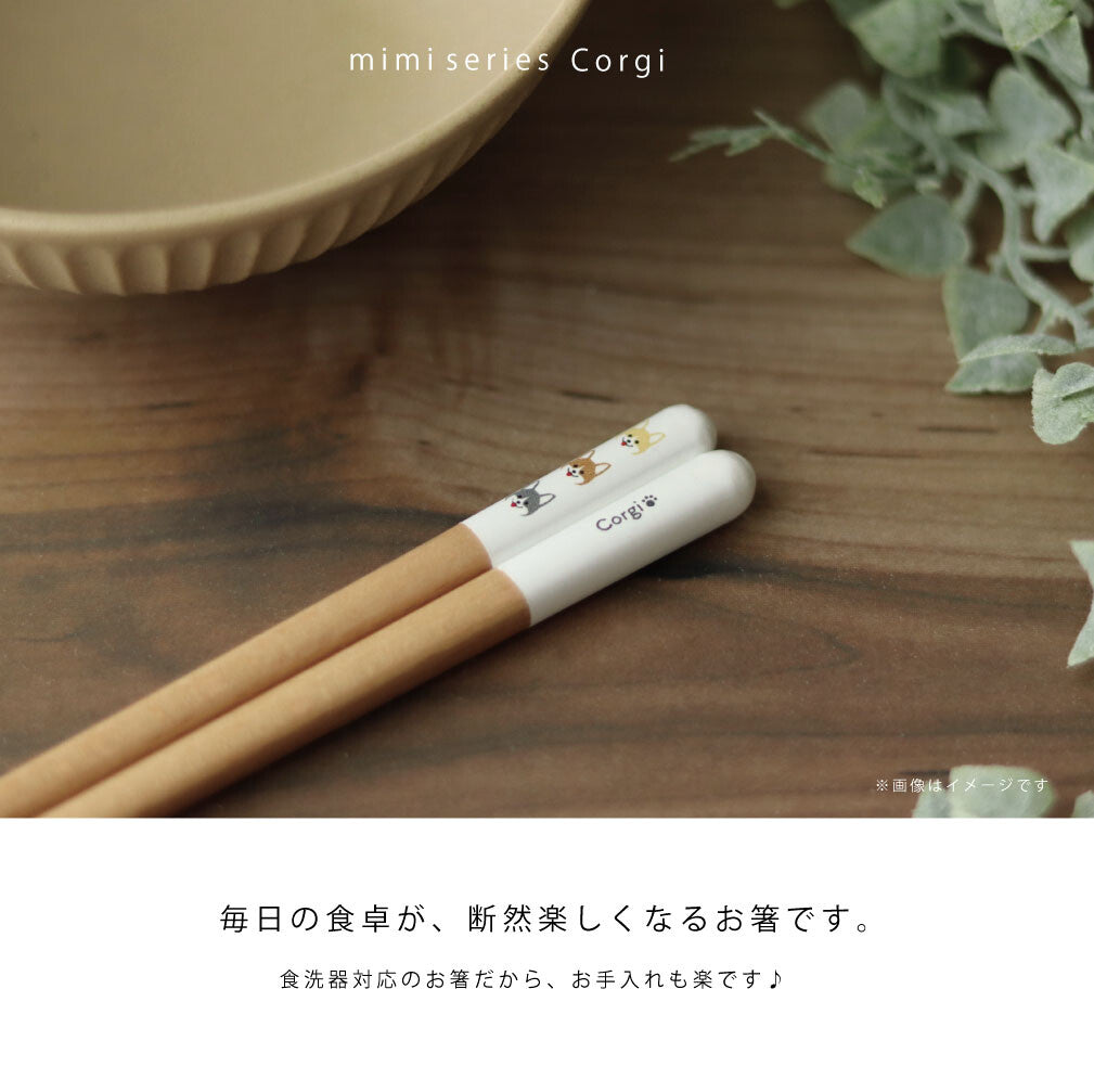 コーギー柄のmimi箸を木の食卓に置いたイメージカット。毎日の食卓が断然楽しくなるお箸、食洗機対応でお手入れも楽との訴求文