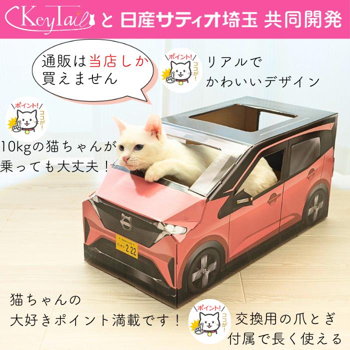 日産サティオ埼玉と共同開発、通販は当店のみで購入可能とアピール。10kgの猫が乗っても大丈夫な強度で、交換用の爪とぎボードが付属する。白猫がピンクの車型ハウスから顔を出している