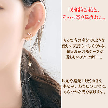 耳元に着けた花と猫モチーフのピアスのアップ。「咲き誇る花と、そっと寄り添うねこ。まるで春の庭を歩くような優しい気持ちにしてくれる、猫とお花のモチーフが愛らしいアクセサリー」の文字