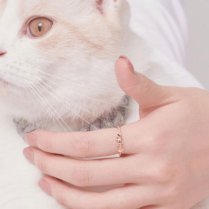 白猫を抱く手の薬指にリングを着けた着用カット。猫の顔とリングを同じフレームに収め、日常使いのイメージを伝える