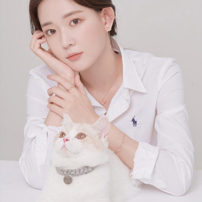 白いシャツ姿の女性が猫を抱きながら頬杖をつくカット。リング・ネックレス・ブレスレットなどWING BLINGアクセサリーを複数箇所に着用した全体コーディネート例