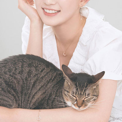 白いブラウスの女性が虎猫を抱いて微笑むカット。ネックレスとブレスレットを着けた首元・腕元のクローズアップ