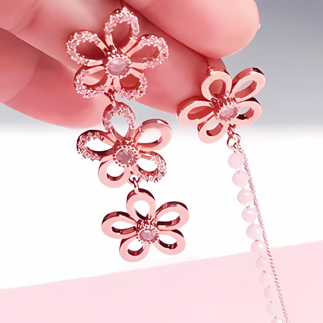 指でつまんで大きさを見せるカット。小花を3つ連ねたロングタイプと、花ひとつにピンクビーズチェーンを垂らしたタイプの2種のピアスのディテール