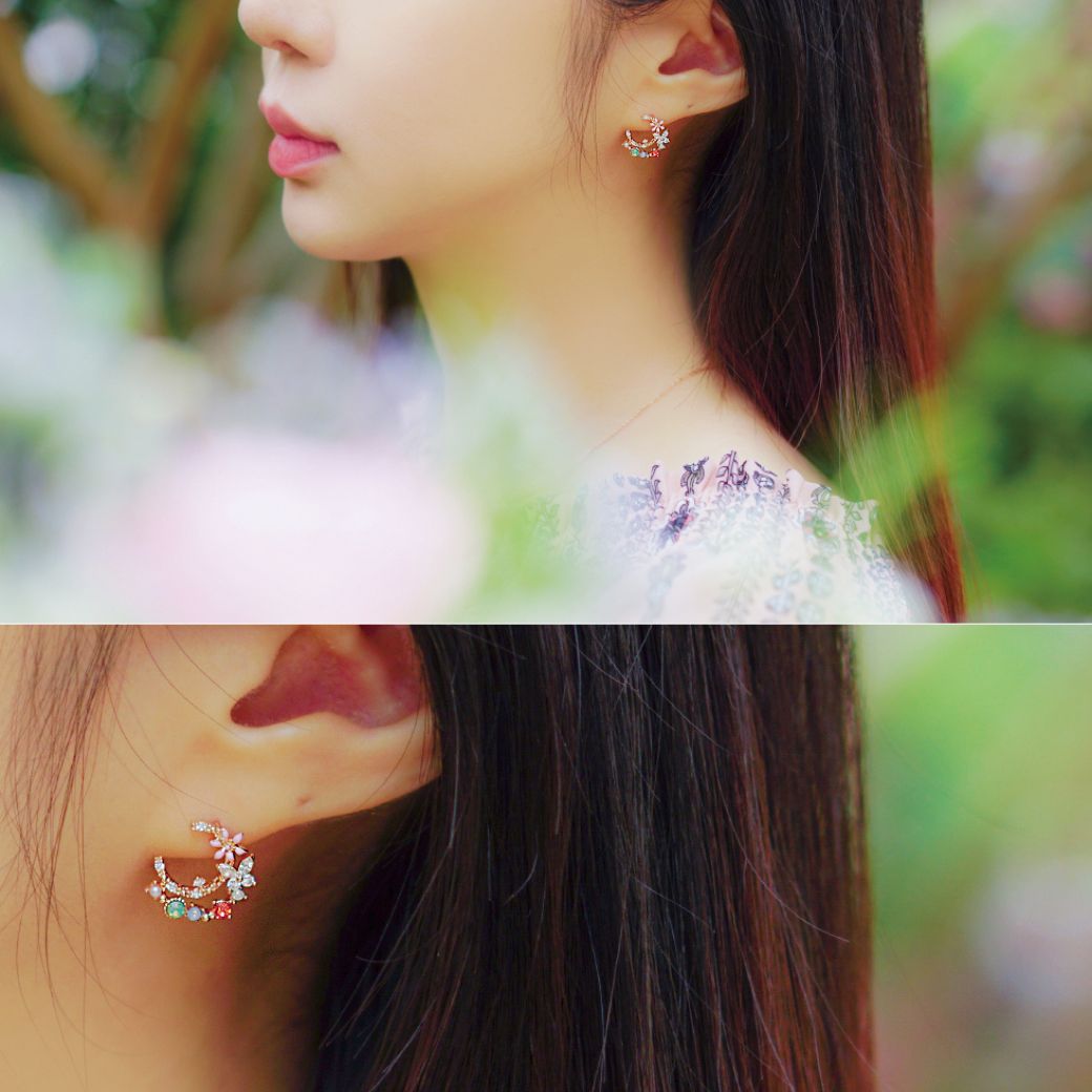 花に囲まれた屋外で三日月ピアスを着けた横顔と、ピアスと耳のクローズアップの2カット。自然光の中でストーンの輝きを見せる着用シーン