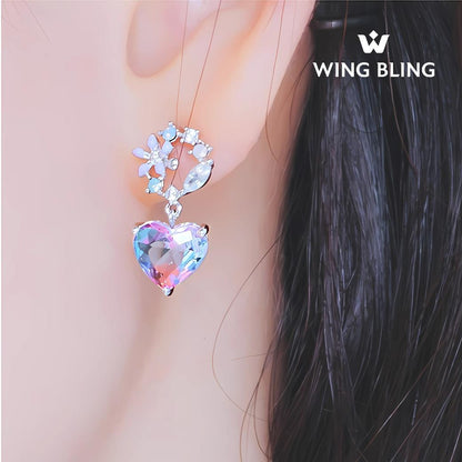 WING BLINGロゴ入り。花モチーフからパープル×ブルーのグラデーションハートが垂れる着用耳元アップ、髪を背景に