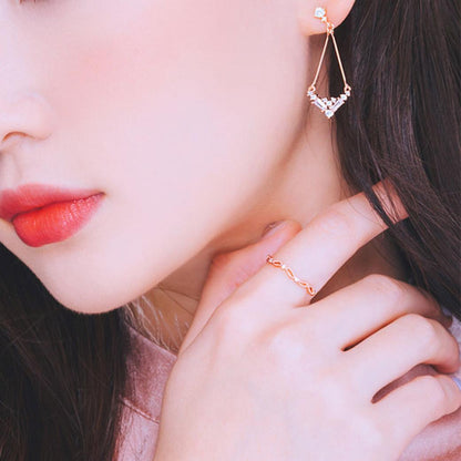 顎に指を添えるモデルの横顔アップ。耳元にドロップピアス、指にリングを着けている