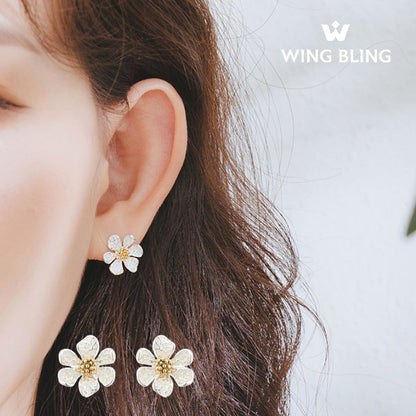 耳に着けた花形イヤリングのアップと、下段に商品単体2個。WING BLINGロゴ入り
