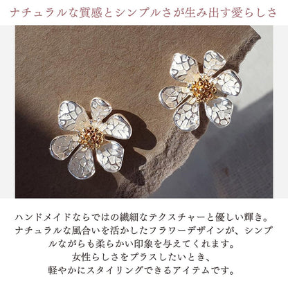 「ナチュラルな質感とシンプルさが生み出す愛らしさ」の見出しと光の中の花形イヤリング2個の写真。ハンドメイドならではの繊細なテクスチャーとナチュラルなフラワーデザインで柔らかい印象を与えると説明