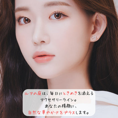 花モチーフイヤリングを着けたモデルの顔アップ。「ルアの庭は、毎日にときめきを添えるアクセサリーライン。あなたの横顔に、自然な華やかさをプラスします。」の説明文