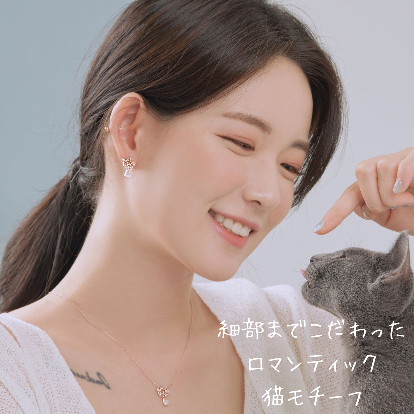 ピアスを着けた女性が猫に指を差し出す笑顔のカット。「細部までこだわったロマンティック猫モチーフ」の文字入り