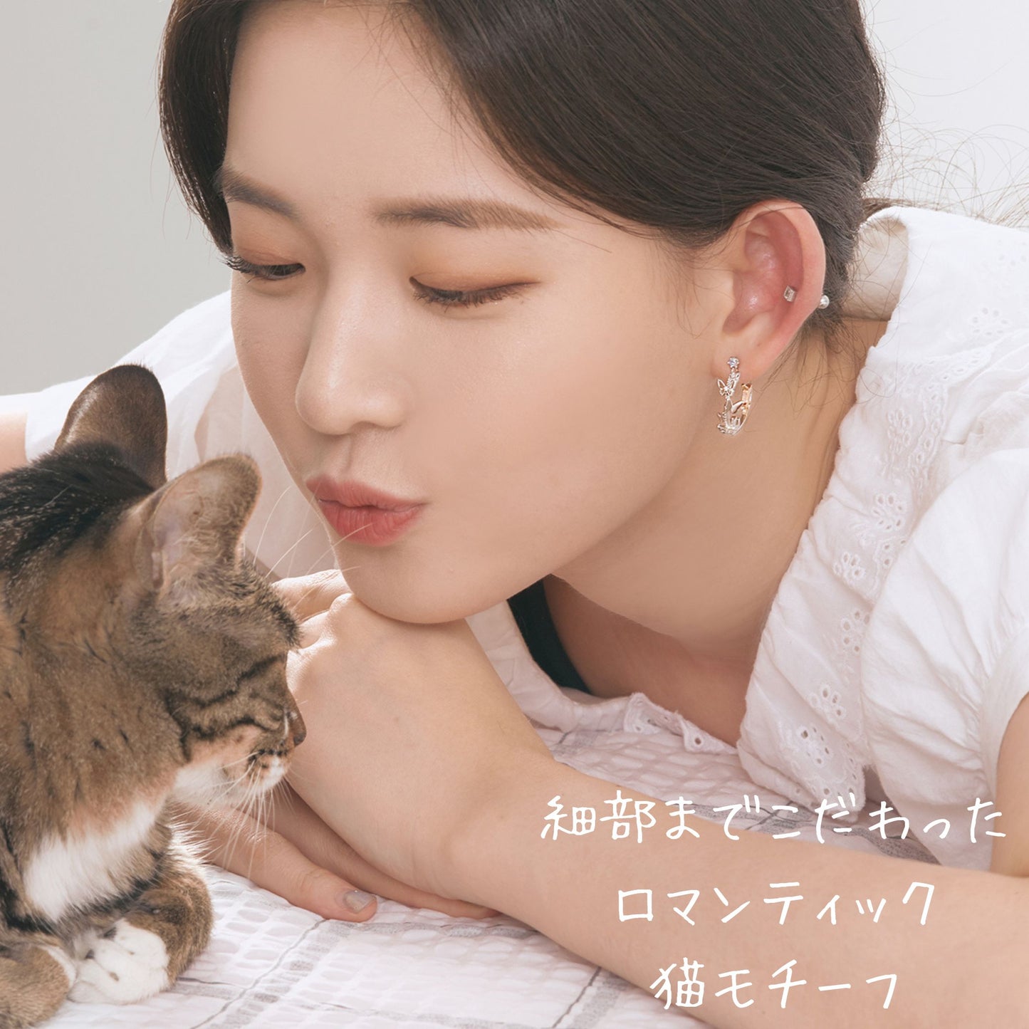 猫に頬を寄せる女性の顔アップ。耳元に着けたピアスが見え、「細部までこだわったロマンティック猫モチーフ」の文字が添えられている。