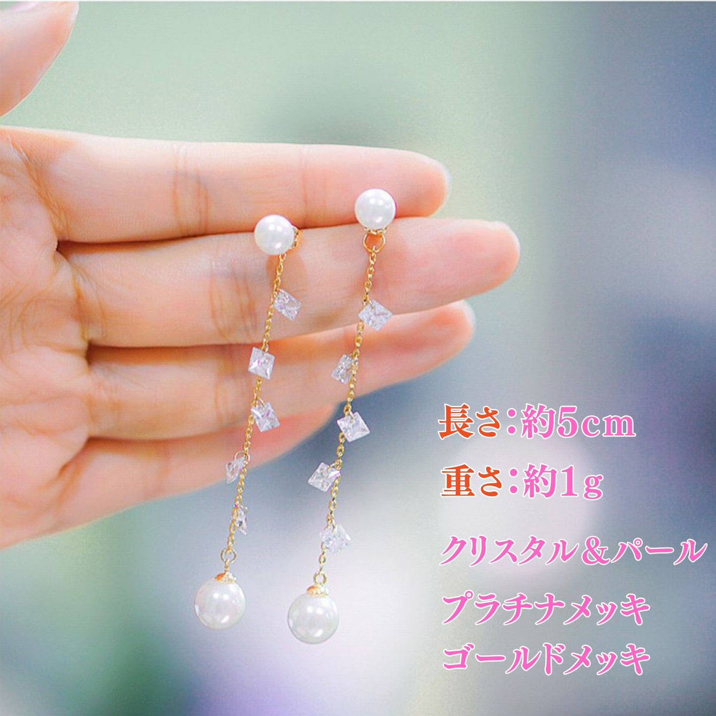 指先に乗せたピアスのサイズ紹介。長さ約5cm・重さ約1g、クリスタル＆パール、プラチナメッキ／ゴールドメッキの表記