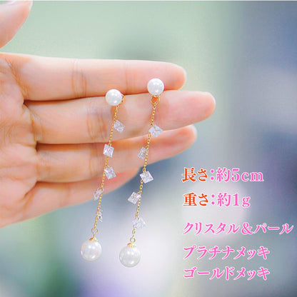 指先に乗せたピアスのサイズ紹介。長さ約5cm・重さ約1g、クリスタル＆パール、プラチナメッキ／ゴールドメッキの表記