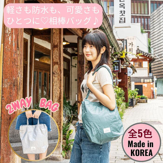 「軽さも防水も、可愛さもひとつに♡相棒バッグ」と添えた導入カット。韓国の街角でグリーンの2WAYバッグを肩掛けする女性、右下に手持ちスタイルの写真と全5色・韓国製の表記