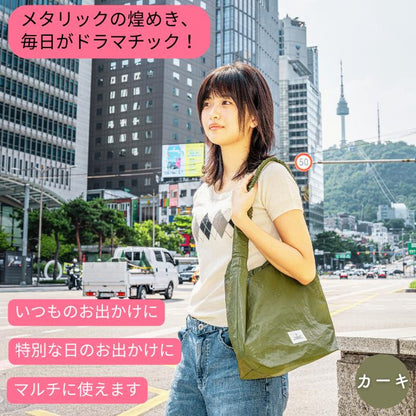 「メタリックの煌めき、毎日がドラマチック！」の見出し。ソウルの街中でカーキ色のバッグを肩掛けする女性、いつものお出かけにも特別な日にも使えると訴求